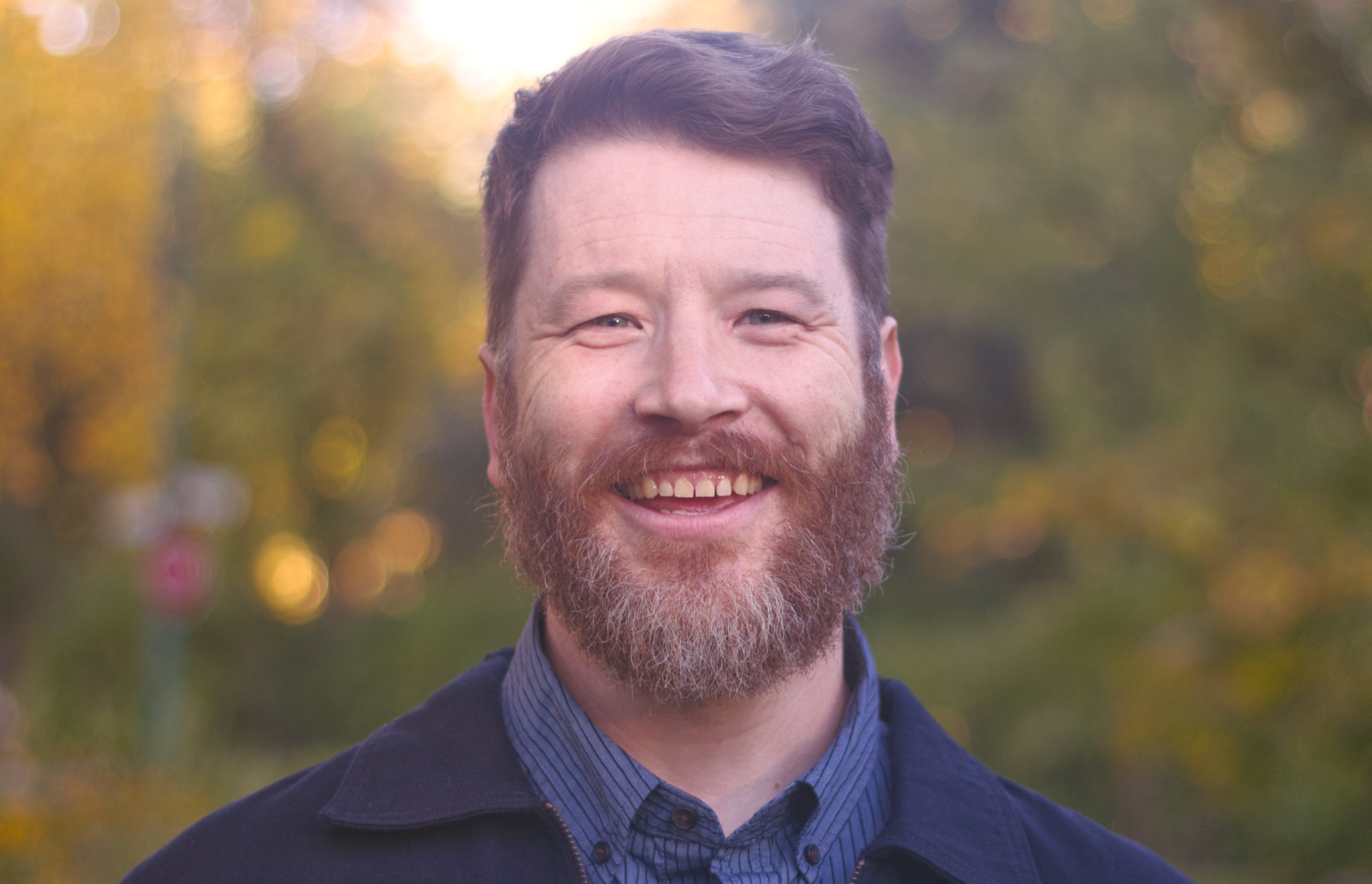 Andrew Kohan, a white man with a beard, smiles while looking straight ahead
